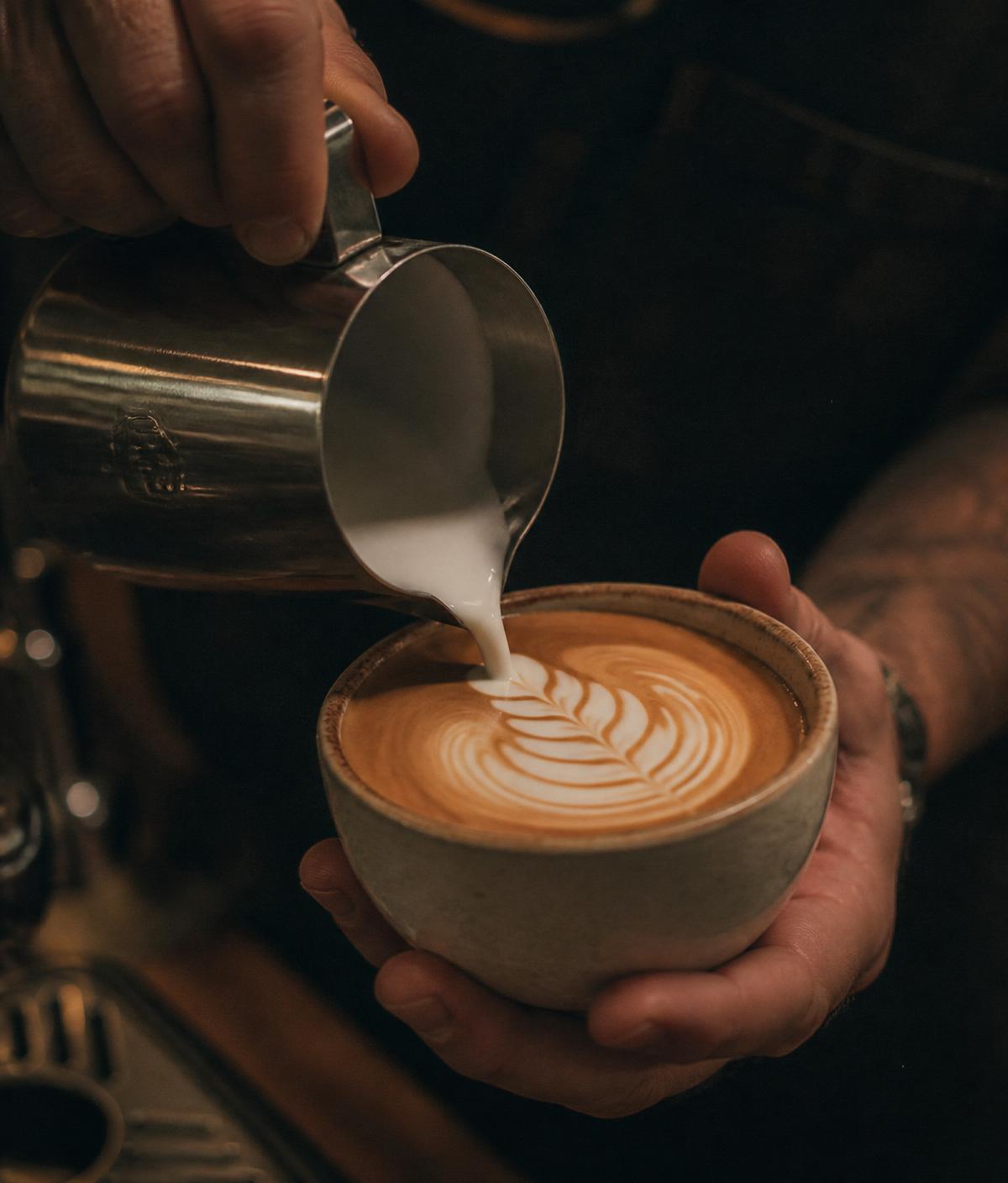 Barista nalewający mleko do filiżanki